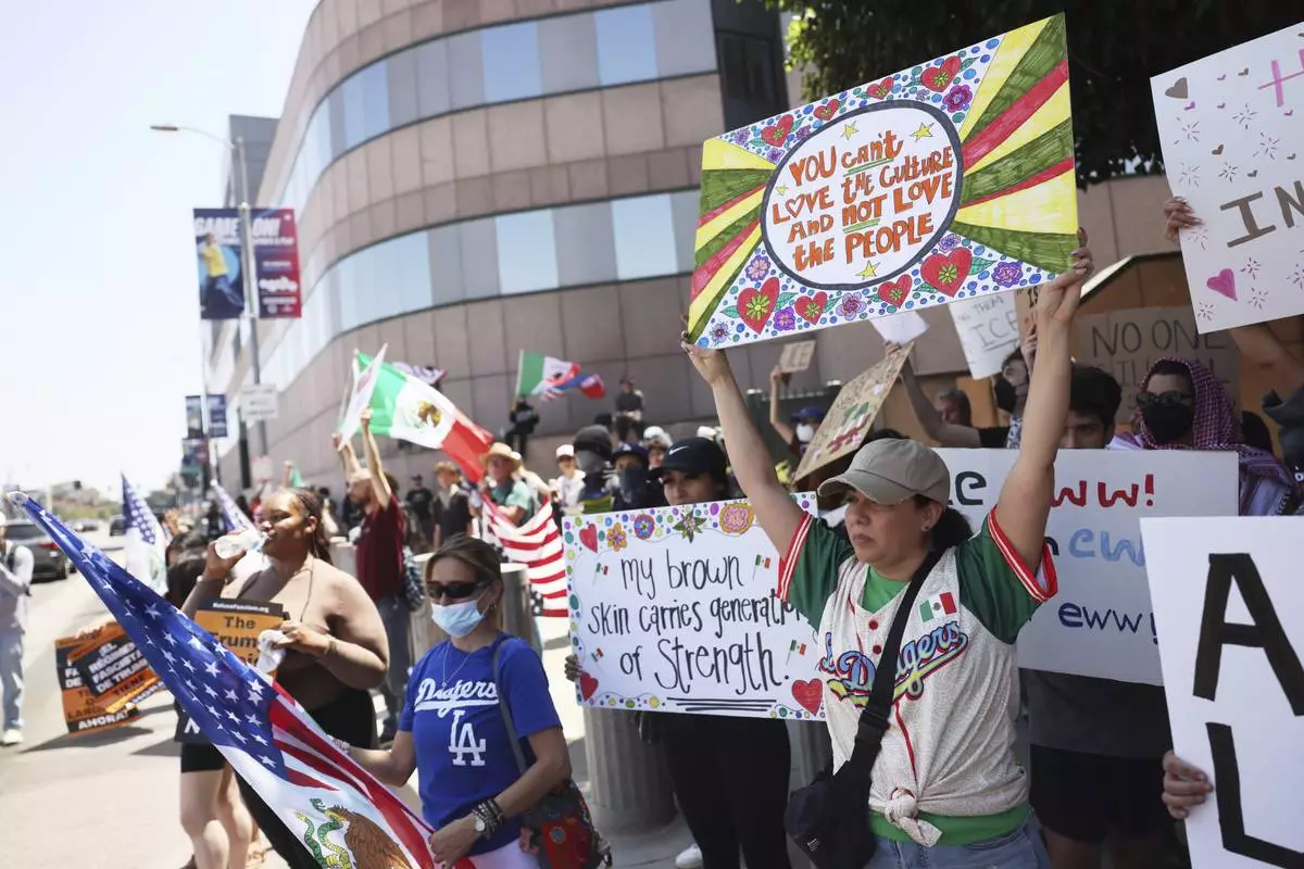 Demonstrators hold signs during a protest, Thursday, June 12, 2025, in Los Angeles. (AP Photo/Etienne Laurent)