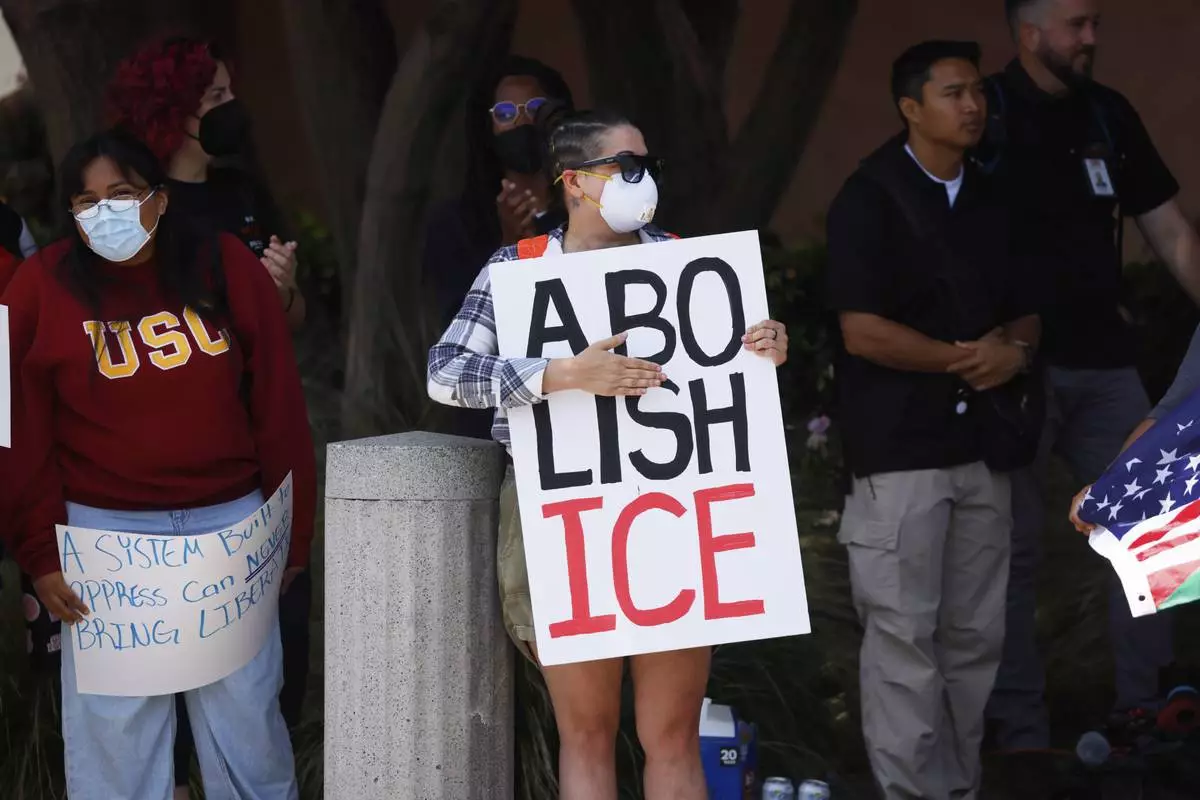 Demonstrators hold signs as they protest, Thursday, June 12, 2025, in Los Angeles. (AP Photo/Etienne Laurent)