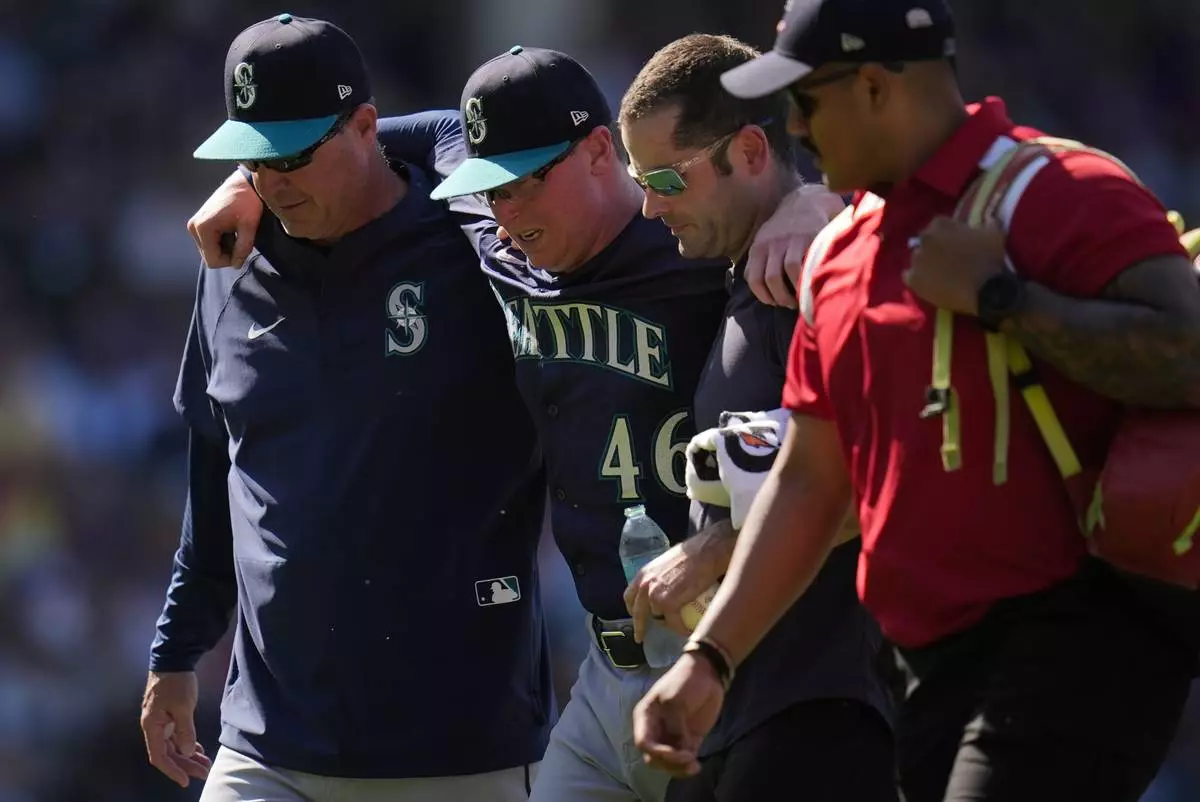 Seattle Mariners pitcher Trent Thornton (46) is helped off the field after suffering from heat exhaustion during the eighth inning of a baseball game against the Chicago Cubs, Saturday, June 21, 2025, in Chicago. (AP Photo/Erin Hooley)