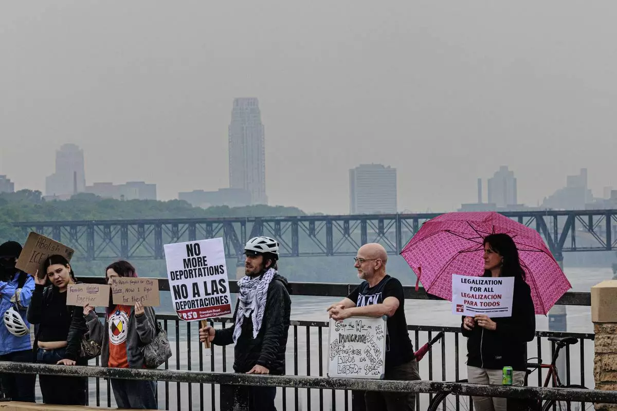 Demonstrators hold signs during a protest against recent immigration raids on the Lake Street-Marshall Bridge on Wednesday, June 11, 2025, in Minneapolis, Minn. (Kerem Yücel/Minnesota Public Radio via AP)