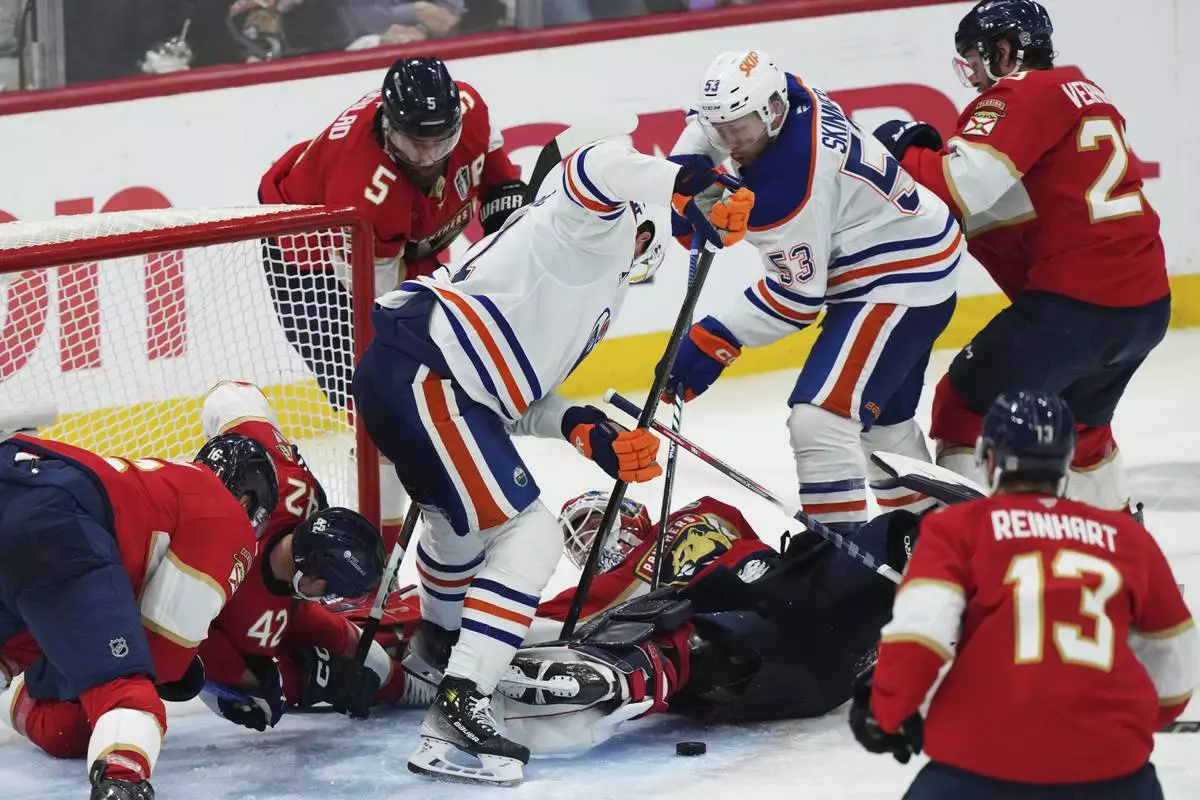 Florida Panthers goalie Sergei Bobrovsky, center bottom, makes a save as Edmonton Oilers' Trent Frederic, center, and Jeff Skinner (53) look for the puck during the first overtime period in Game 4 of the NHL hockey Stanley Cup Final in Sunrise, Fla., Thursday, June 12, 2025. (Nathan Denette/The Canadian Press via AP)