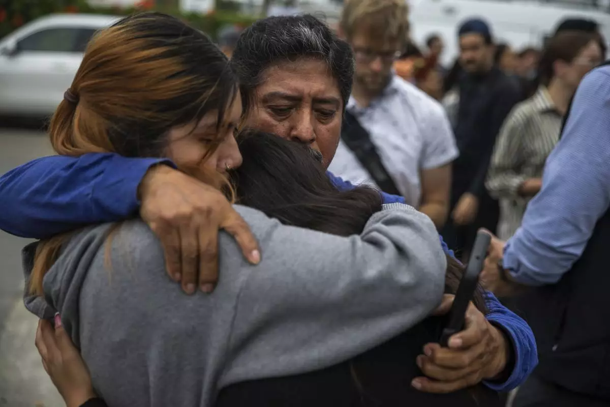 Jaslyn Hernandez, daughter of a car wash worker, embraces her sister Kimberly Hernandez, and their uncle Juan Medina during a press conference with families of detained car wash workers Wednesday, June 11, 2025, in Culver City, Calif. (AP Photo/Ethan Swope)