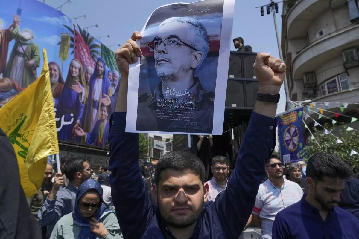 An Iranian protester holds up a poster of Chief of General Staff of the Armed Forces Mohammad Bagheri, who was killed in an Israeli strike, in an anti-Israeli gathering in Tehran, Iran, Friday, June 13, 2025. (AP Photo/Vahid Salemi)