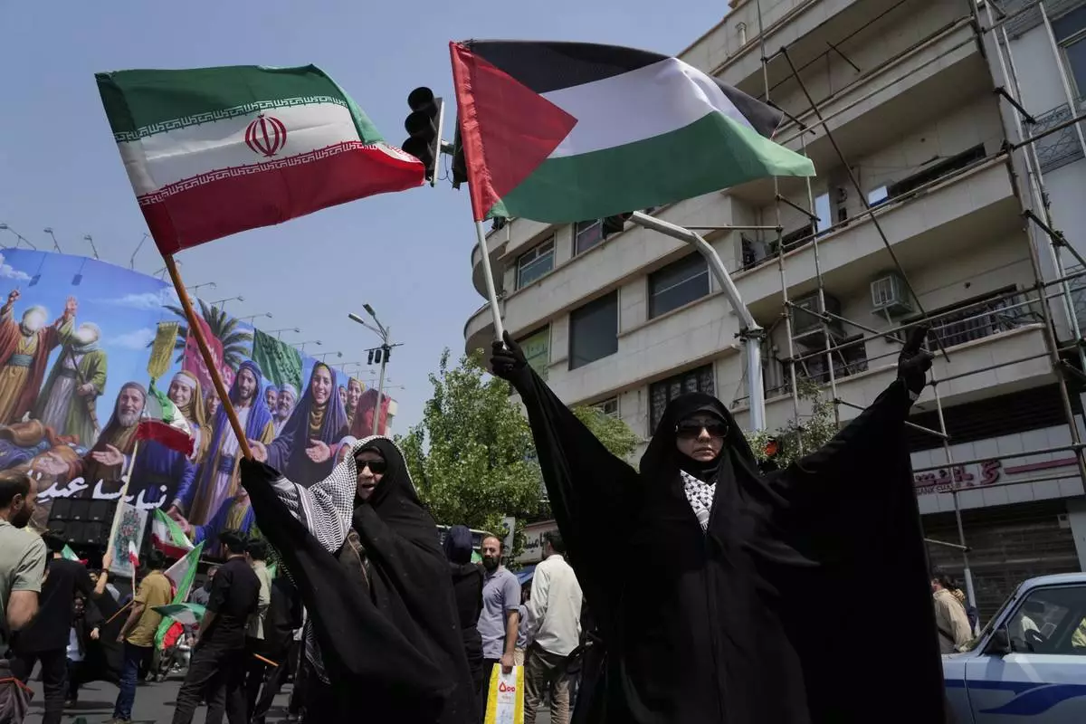 Iranian protesters hold up Iranian and Palestinian flags in an anti-Israeli gathering in Tehran, Iran, Friday, June 13, 2025. (AP Photo/Vahid Salemi)