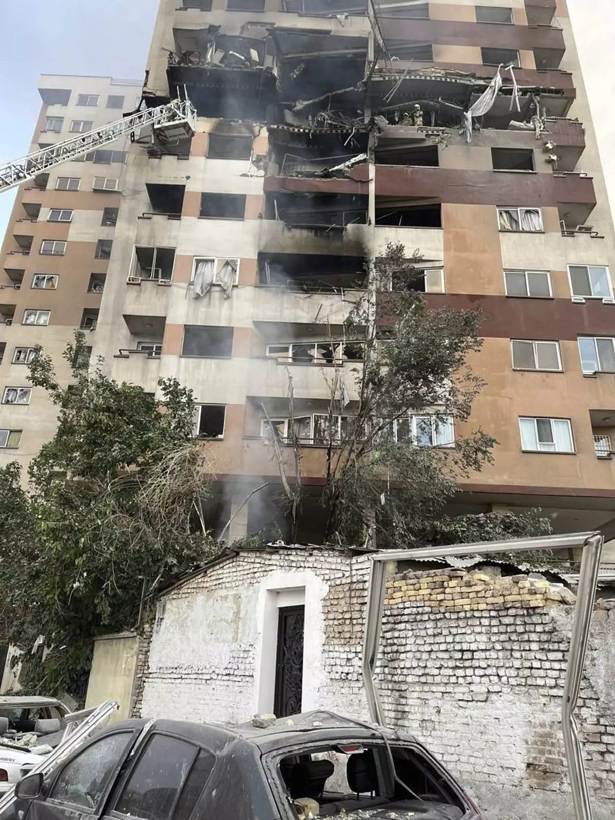 Firemen work at an apartment building after it was hit in Tehran, Iran, early Friday, June 13, 2025. Israel attacked Iran's capital early Friday, with explosions booming across Tehran.(AP Photo/Vahid Salemi)