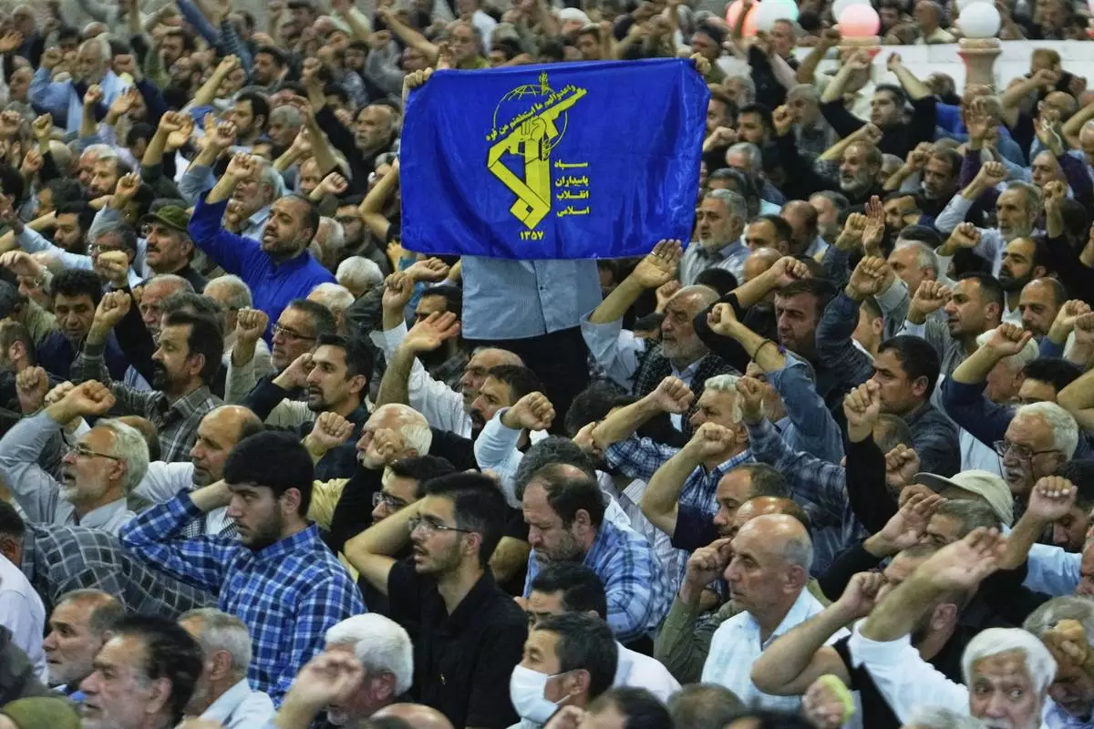 An Iranian worshipper holds up a banner containing the Revolutionary Guard emblem as the others chant slogans during Friday prayers ceremony at Tehran University campus in Tehran, Iran, Friday, June 13, 2025. (AP Photo/Vahid Salemi)