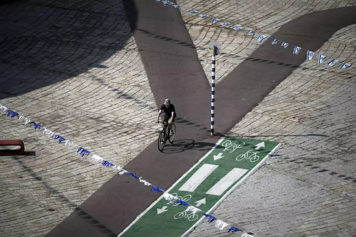 A man rides a bicycle along the empty promenade on Tel Aviv's beachfront, Friday, June 13, 2025. (AP Photo/Leo Correa)