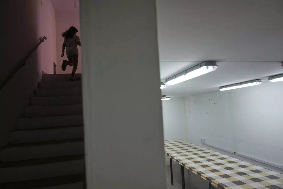 A girl runs to a bomb shelter in an apartment building in Hadera, Israel, Friday June 13, 20025. (AP Photo/Ariel Schalit)