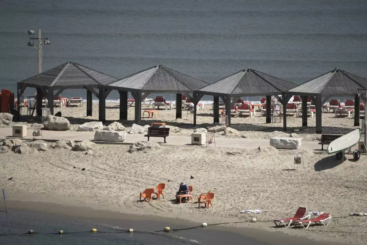 A man sits on the empty beach along Tel Aviv's beachfront, Friday, June 13, 2025. (AP Photo/Leo Correa)