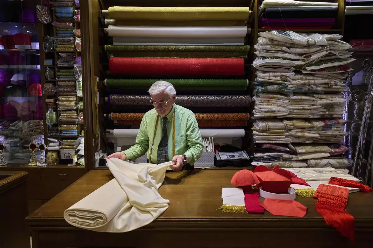 FILE - Italian tailor Raniero Mancinelli, 87, prepares the white fabric to create suits, in three different sizes, to be taken to the Vatican in the hope that it might be worn by the new pope, at his shop in Rome, April 24, 2025. (AP Photo/Bernat Armangue, File)