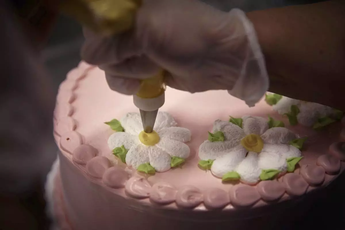 An employee decorates a cake inside Walmart Supercenter on Wednesday, May 28, 2025, in North Bergen, N.J. (AP Photo/Andres Kudacki)