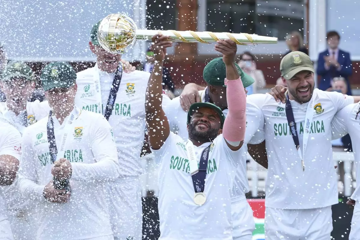 South Africa's captain Temba Bavuma holds the winner's trophy and celebrates with teammates after their win in the World Test Championship final against Australia at Lord's cricket ground in London, Saturday, June 14, 2025. (AP Photo/Kirsty Wigglesworth)