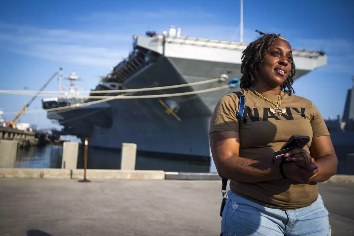 Latoya Savoy stands in front of the USS Gerald R. Ford aircraft carrier leaves Naval Station Norfolk with her daughter (unnamed), a U.S. Navy sailor who works in aviation ordinance on Tuesday, June 24, 2025, in Norfolk, Va. (AP Photo/John Clark)