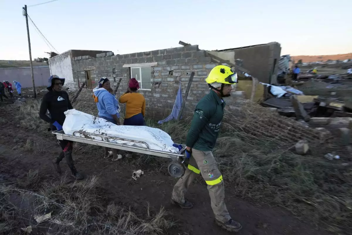 Rescue workers transport a person in a body bag after floods swept through the area in Mthatha, South Africa, Thursday, June 12, 2025. (AP Photo/Themba Hadebe)