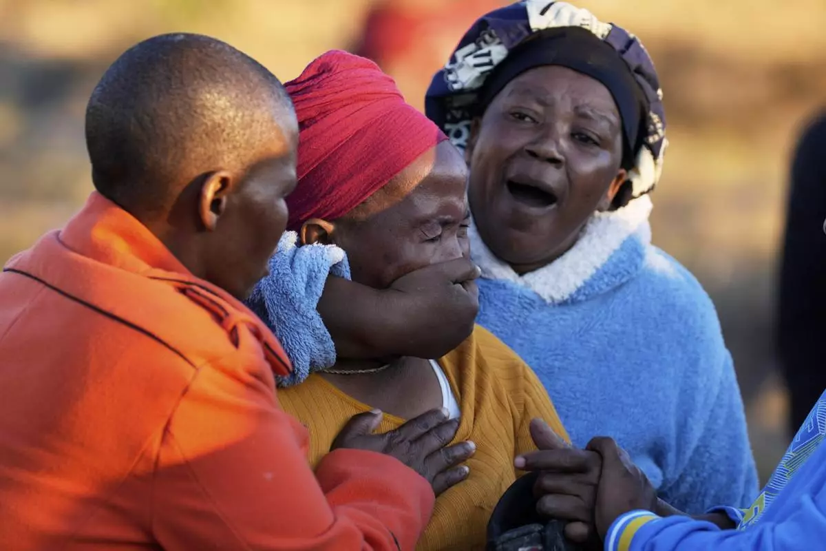 A woman is consoled by community members as bodies of her sister and three daughters were retrieved from inside a one room house, after floods swept through the area in Mthatha, South Africa, Thursday, June 12, 2025. (AP Photo/Themba Hadebe)