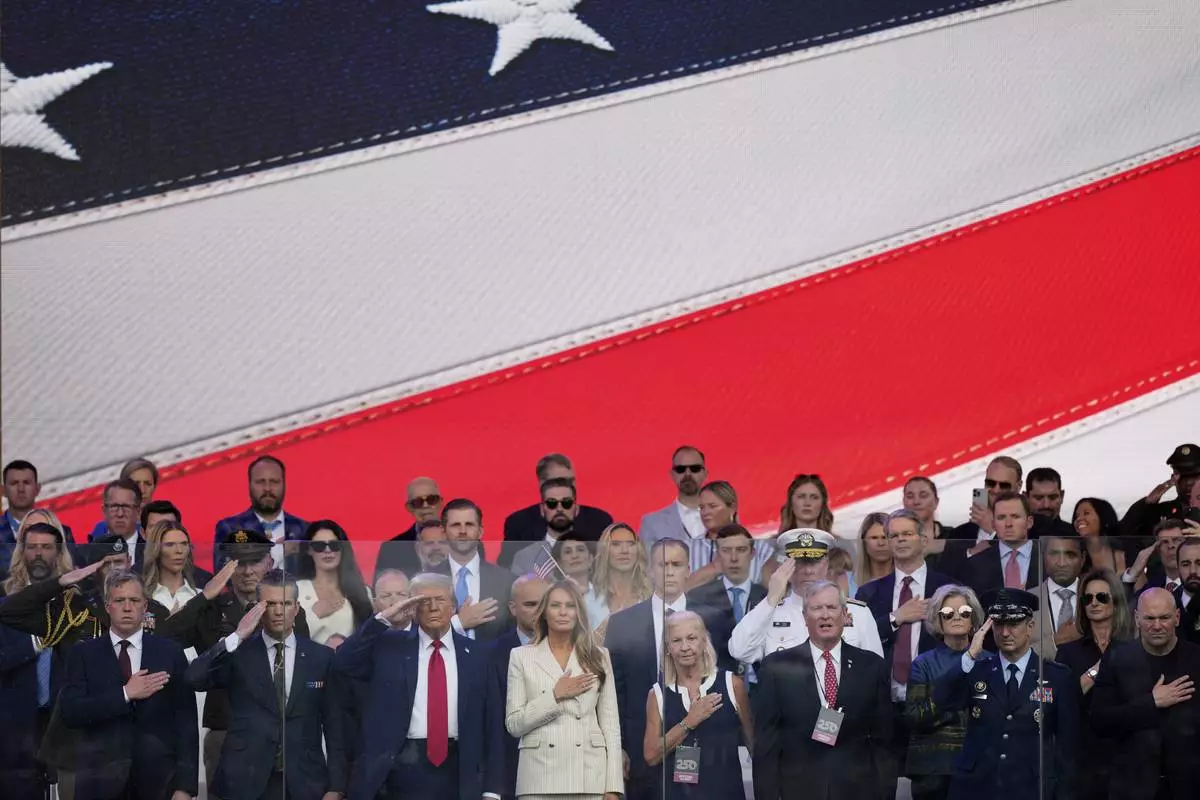 President Donald Trump, first lady Melania Trump, and other guests stand for the National Anthem, during a military parade commemorating the Army's 250th anniversary, coinciding with his 79th birthday, Saturday, June 14, 2025, in Washington. (AP Photo/Julia Demaree Nikhinson)