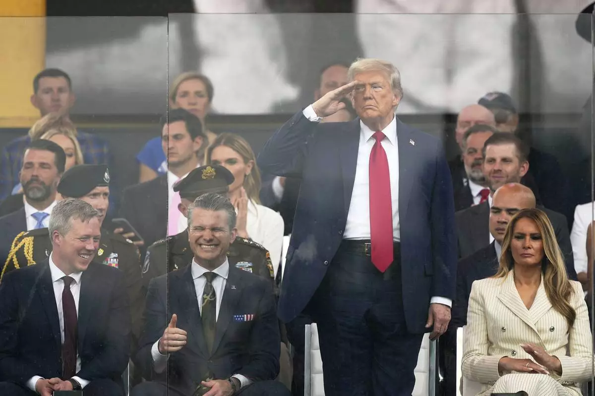 President Donald Trump salutes as attends a military parade commemorating the Army's 250th anniversary, coinciding with his 79th birthday, Saturday, June 14, 2025, in Washington, as Secretary of the Army Daniel Driscoll, Defense Secretary Pete Hegseth, and first lady Melania Trump, watch. (AP Photo/Julia Demaree Nikhinson)