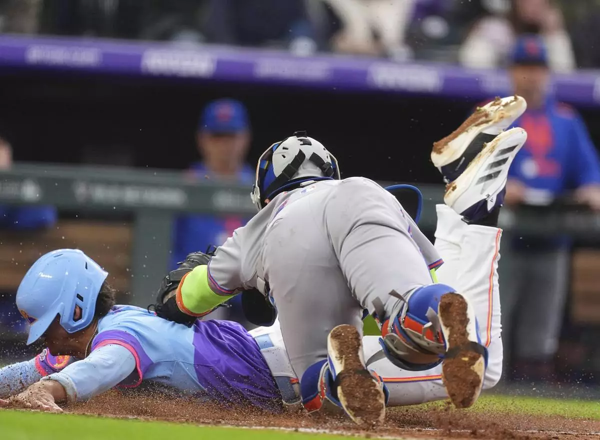 New York Mets catcher Francisco Alvarez, front, tags out Colorado Rockies' Ryan Ritter as he tries to score on a ground ball hit by Mickey Moniak in the fifth inning of a baseball game Friday, June 6, 2025, in Denver. (AP Photo/David Zalubowski)