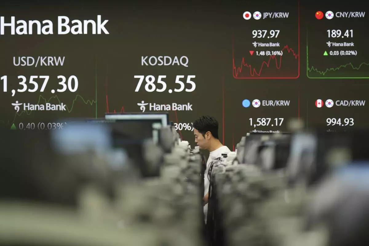 A dealer walks past near screens showing the foreign exchange rate between U.S. dollar and South Korean won and South Korean won and the Korean Securities Dealers Automated Quotations (KOSDAQ) at a dealing room of Hana Bank in Seoul, South Korea, Friday, June 27, 2025. (AP Photo/Lee Jin-man)