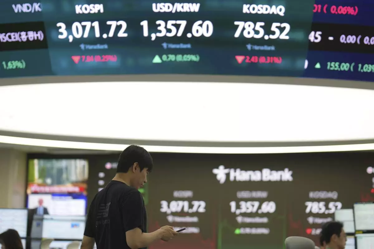 A dealer walks past near screens showing the Korea Composite Stock Price Index (KOSPI), left, the foreign exchange rate between U.S. dollar and South Korean won and South Korean won and the Korean Securities Dealers Automated Quotations (KOSDAQ) at a dealing room of Hana Bank in Seoul, South Korea, Friday, June 27, 2025. (AP Photo/Lee Jin-man)