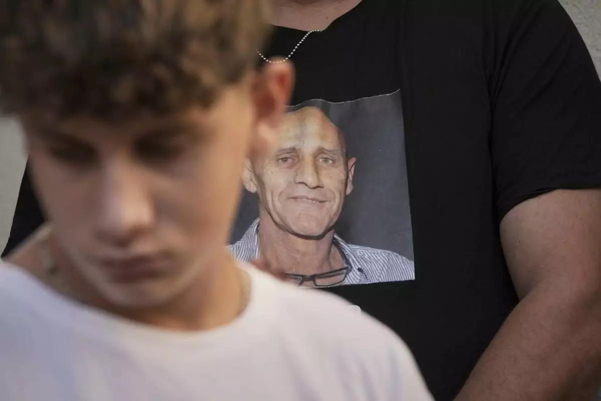 A relative of slain hostage Yair Yaakov wears a T-shirt with his picture on it as the family reads a statement to journalists in Gan Yavne, Israel, following the return of his body from the Gaza Strip, Thursday, June 12, 2025. (AP Photo/Maya Alleruzzo)