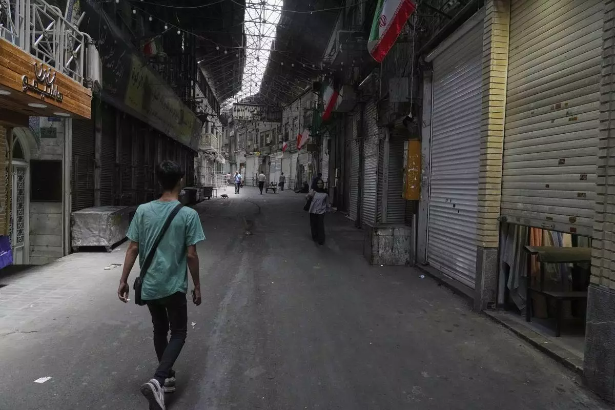 Few pedestrians walk along the historic Grand Bazaar as shops remain shuttered, in Tehran, Iran, Monday, June 16, 2025. (AP Photo/Vahid Salemi)