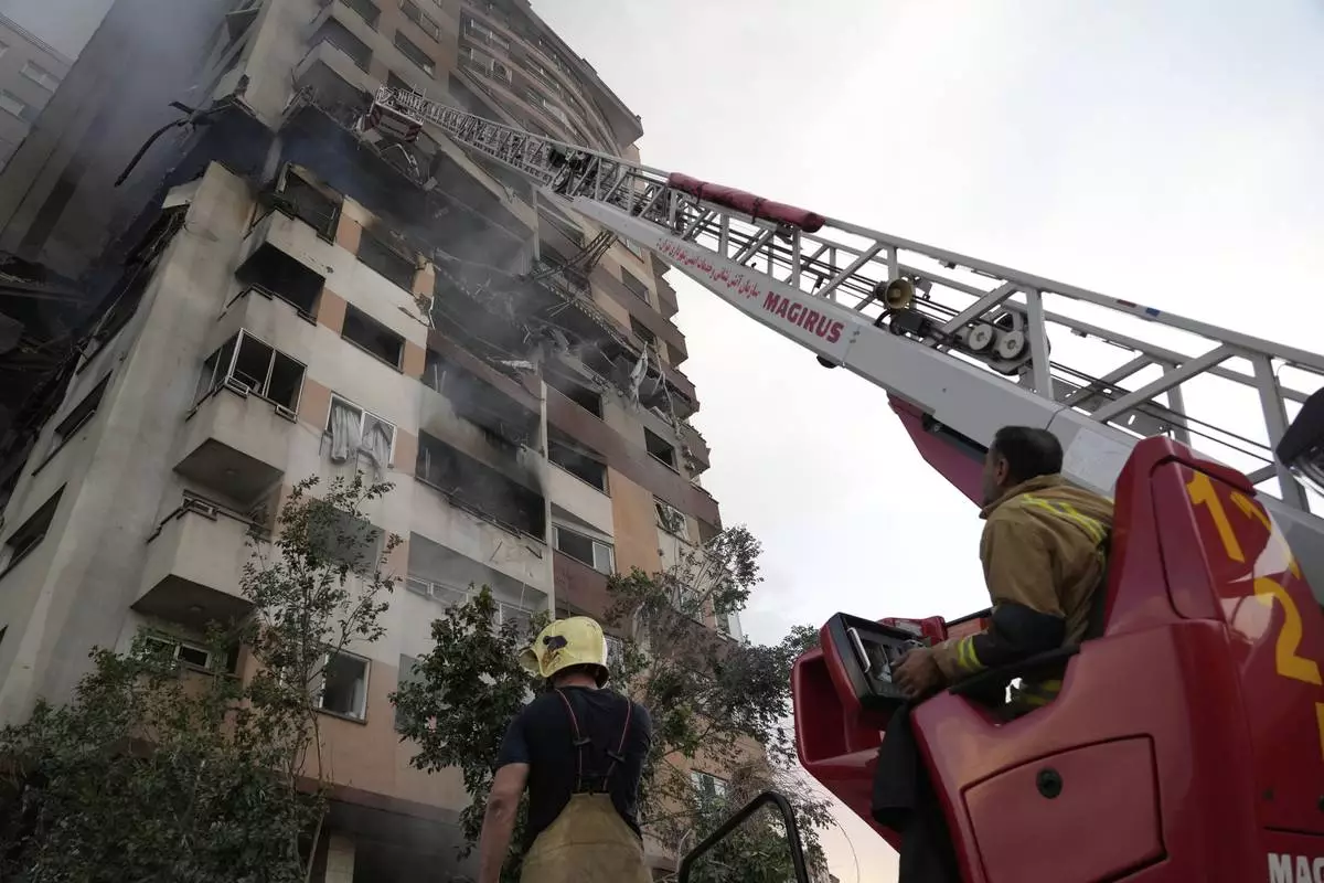 Firefighters work the scene of an explosion at a residence compound in northern Tehran, Iran, Friday, June 13, 2025. (AP Photo/Vahid Salemi)