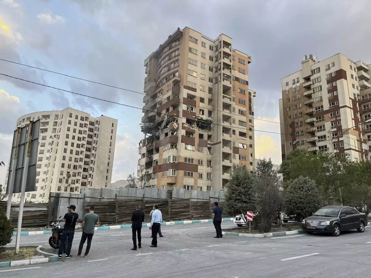 Residents watch a damaged apartment in Tehran, Iran, early Friday, June 13, 2025. Israel attacked Iran's capital early Friday, with explosions booming across Tehran.(AP Photo/Vahid Salemi)