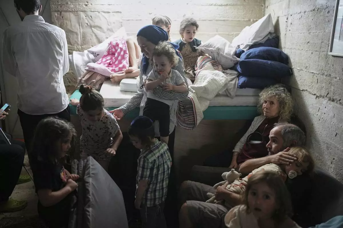 Israelis take shelter in a basement as a siren sounds a warning following missile launches from Iran, in Jerusalem, Sunday, June 15, 2025. (AP Photo/Ohad Zwigenberg)