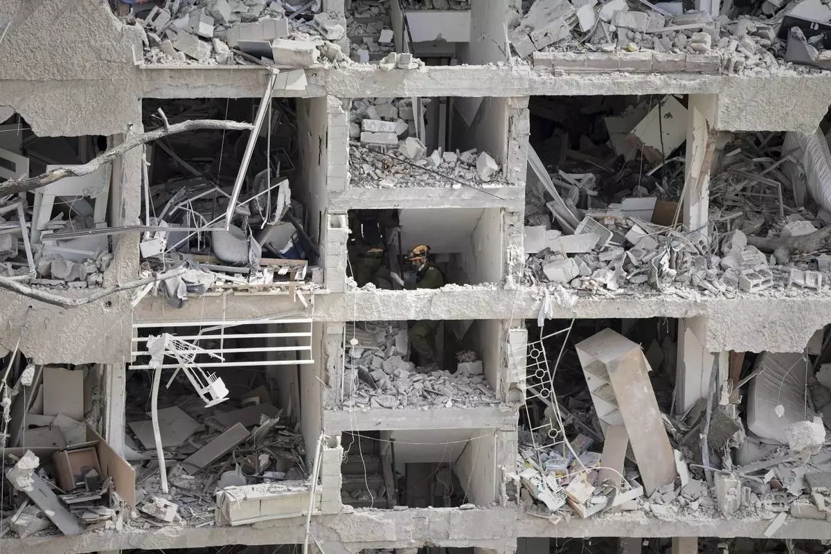Israel's home front command officers survey the site of a direct missile strike launched from Iran in Tel Aviv, Israel, Sunday, June 22, 2025. (AP Photo/Oded Balilty)