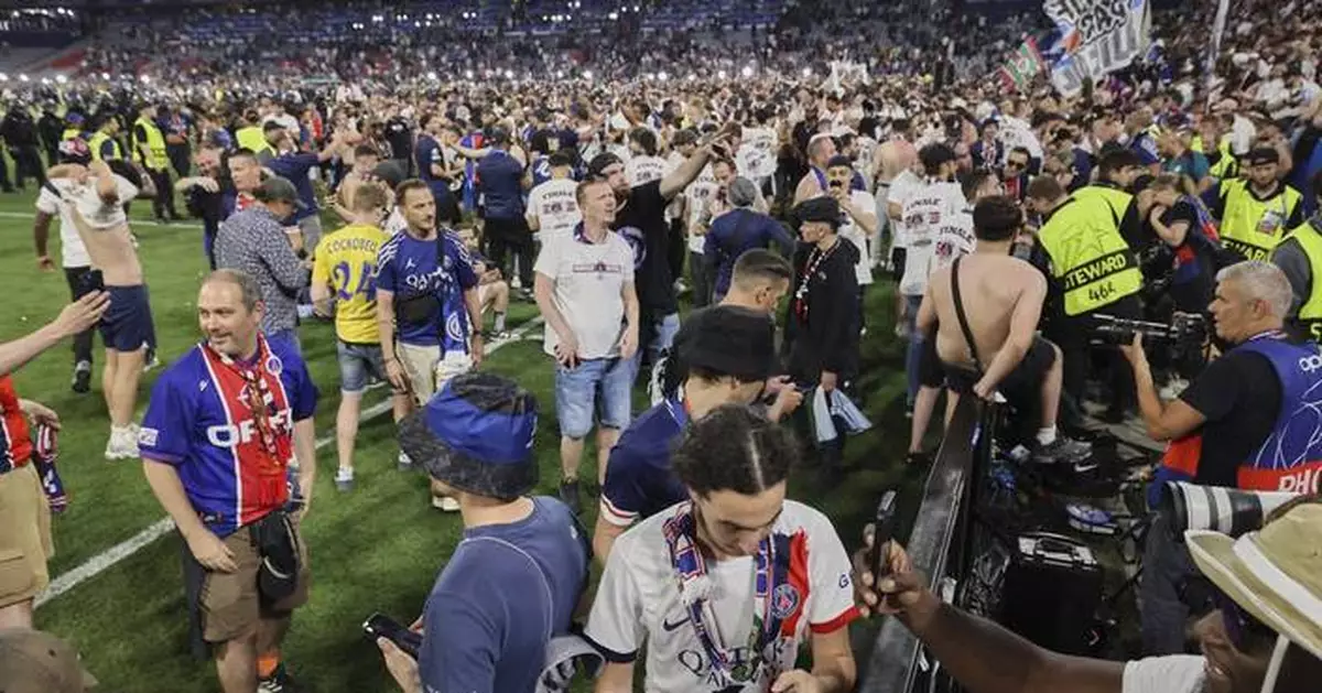 Police have to hold back PSG fans as they try to rush the field after Champions League win