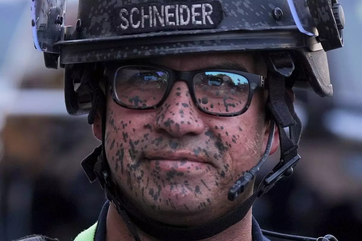 A police officer's face is covered in pepper spray outside the Metropolitan Detention Center of downtown Los Angeles, Sunday, June 8, 2025, following last night's immigration raid protest. (AP Photo/Jae Hong)