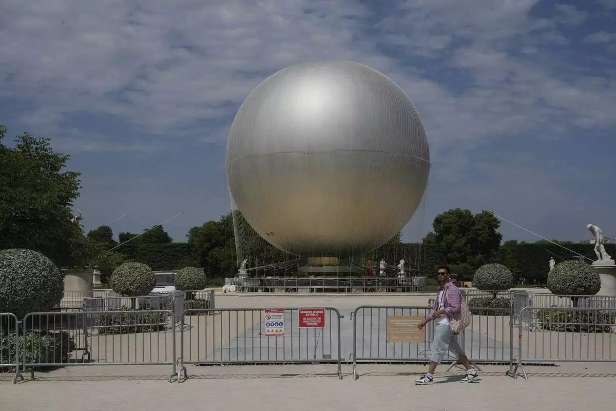 A man walks past the Olympic cauldron at the Tuileries Gardens, ahead of its nightly summer relaunch starting June 21, in Paris, Thursday, June 12, 2025. (AP Photo/Michel Euler)