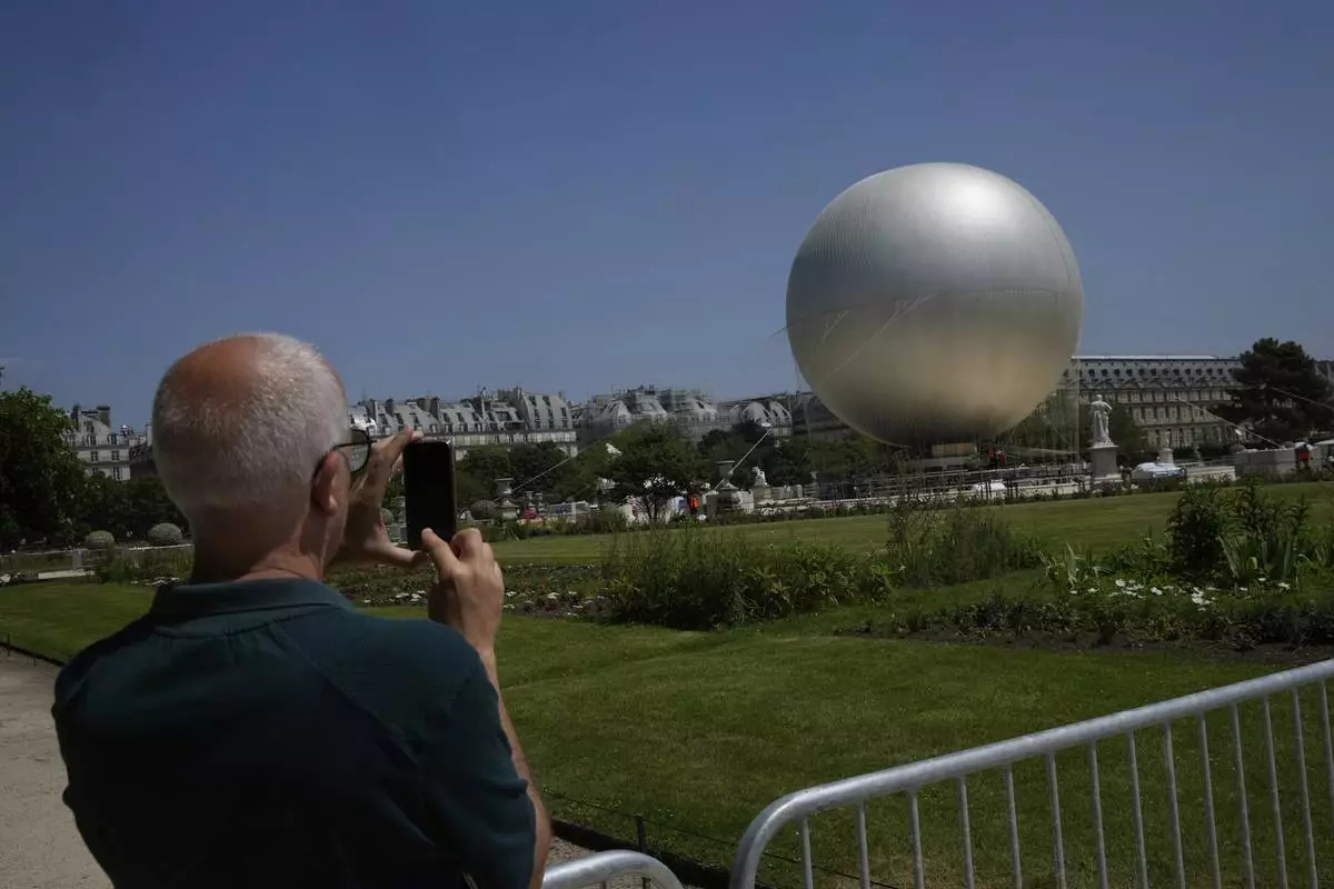 A man takes a snapshot of the Olympic cauldron at the Tuileries Gardens, ahead of its nightly summer relaunch starting June 21, in Paris, Thursday, June 12, 2025. (AP Photo/Michel Euler)