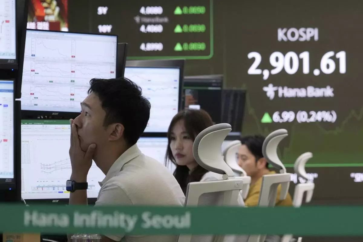 A currency trader watches monitors near a screen showing the Korea Composite Stock Price Index (KOSPI) at the foreign exchange dealing room of the KEB Hana Bank headquarters in Seoul, South Korea, Monday, June 16, 2025. (AP Photo/Ahn Young-joon)