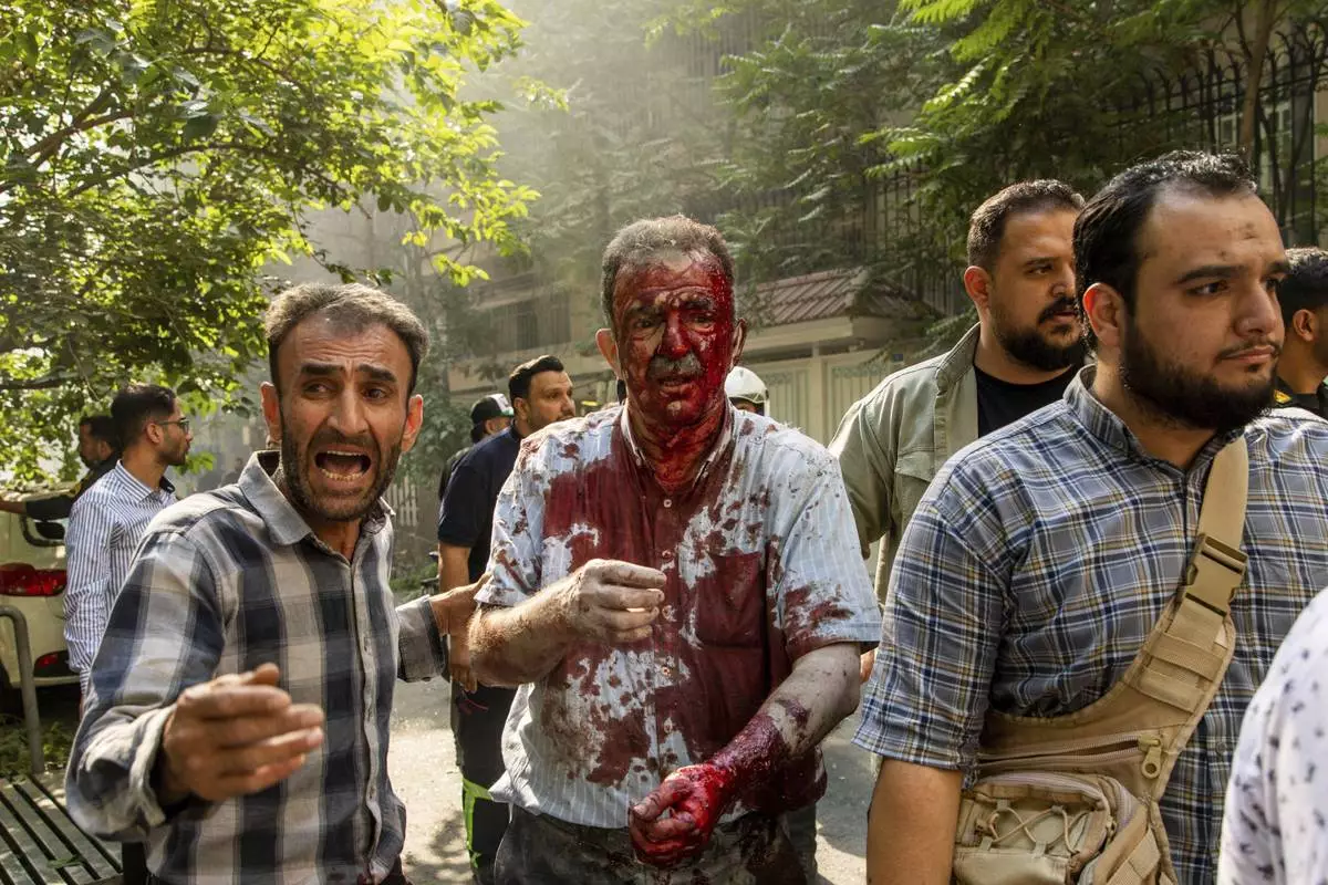 CORRECTS BYLINE.- An injured man is helped to leave the scene after an explosion in downtown Tehran, amid Israel's three-day campaign of strikes against Iran, Sunday, June 15, 2025. (AP Photo/Majid Khahi/ISNA)