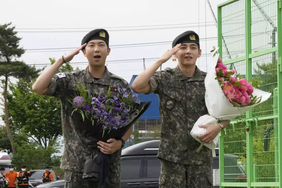 K-pop band BTS members RM, left, and V salute after being discharged from a mandatory military service in Chuncheon, South Korea, Tuesday, June 10, 2025. (AP Photo/Ahn Young-joon)