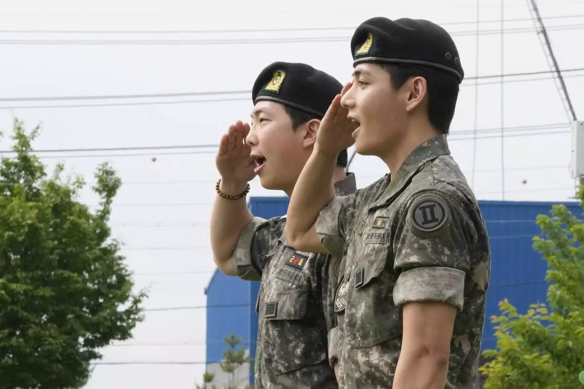K-pop band BTS members RM, left, and V salute after being discharged from a mandatory military service in Chuncheon, South Korea, Tuesday, June 10, 2025. (AP Photo/Ahn Young-joon)