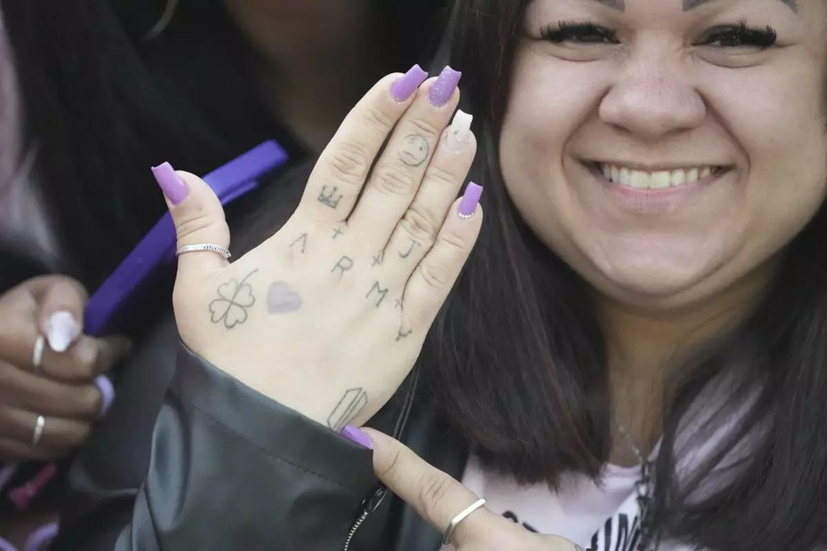 Daiane Matos from Brazil, 37, shows her hand as she waits for arrival of K-pop band BTS members Jimin and Jung Kook in Yeoncheon, South Korea, Wednesday, June 11, 2025. (AP Photo/Lee Jin-man)