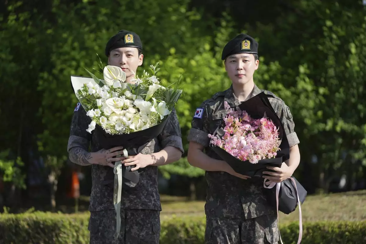 K-pop band BTS members Jimin, right, and Jung Kook hold bouquets after being discharged from a mandatory military service in Yeoncheon, South Korea, Wednesday, June 11, 2025. (AP Photo/Lee Jin-man)