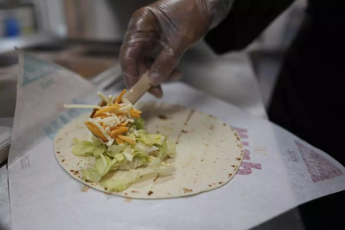Charles L. Krumsiek, a McDonald's chef, puts cheese on a tortilla to make a snack wrap at McDonald's Headquarter in Chicago, Thursday, May 29, 2025. (AP Photo/Nam Y. Huh)