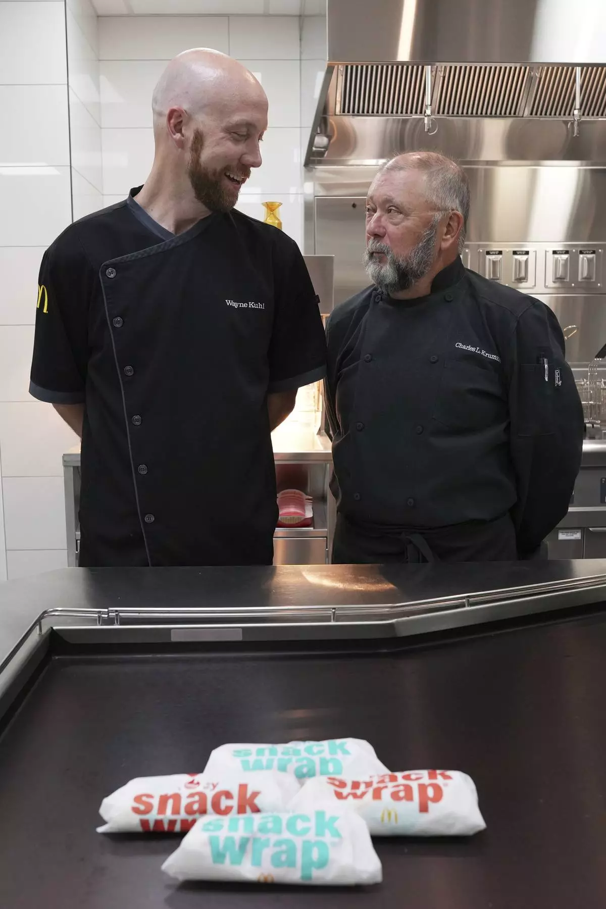 Wayne Kuhl, left, and Charles L. Krumsieka, McDonald's chefs look at each other after made snack wraps at McDonald's Headquarter in Chicago, Thursday, May 29, 2025. (AP Photo/Nam Y. Huh)