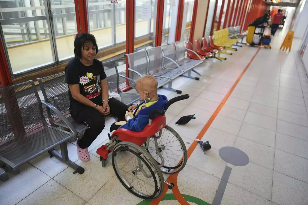 Lucia Ruiz Diaz sits next to her 5-year-old son Tomas, who has cancer, at a waiting room in the Garrahan Hospital in Buenos Aires, Argentina, Tuesday, April 29, 2025. Cancer patients say they've grown sicker since Argentina's libertarian President Javier Milei took his chainsaw to the public health system. (AP Photo/Natacha Pisarenko)