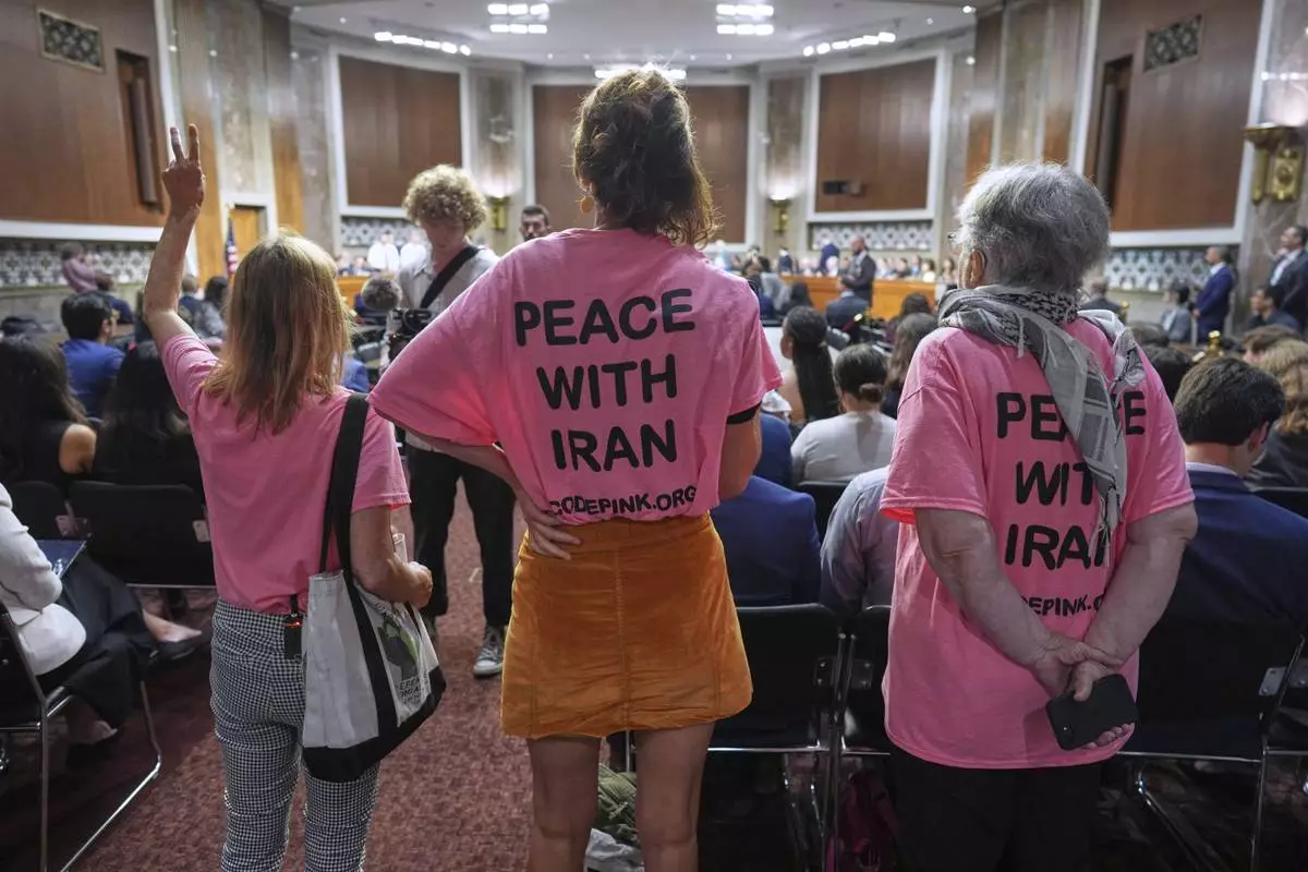 Activists stand up in the hearing room as Secretary of Defense Pete Hegseth arrives to field questions on the Pentagon budget and the crisis between Iran and Israel from the Senate Armed Services Committee, at the Capitol in Washington, Wednesday, June 18, 2025. (AP Photo/J. Scott Applewhite)
