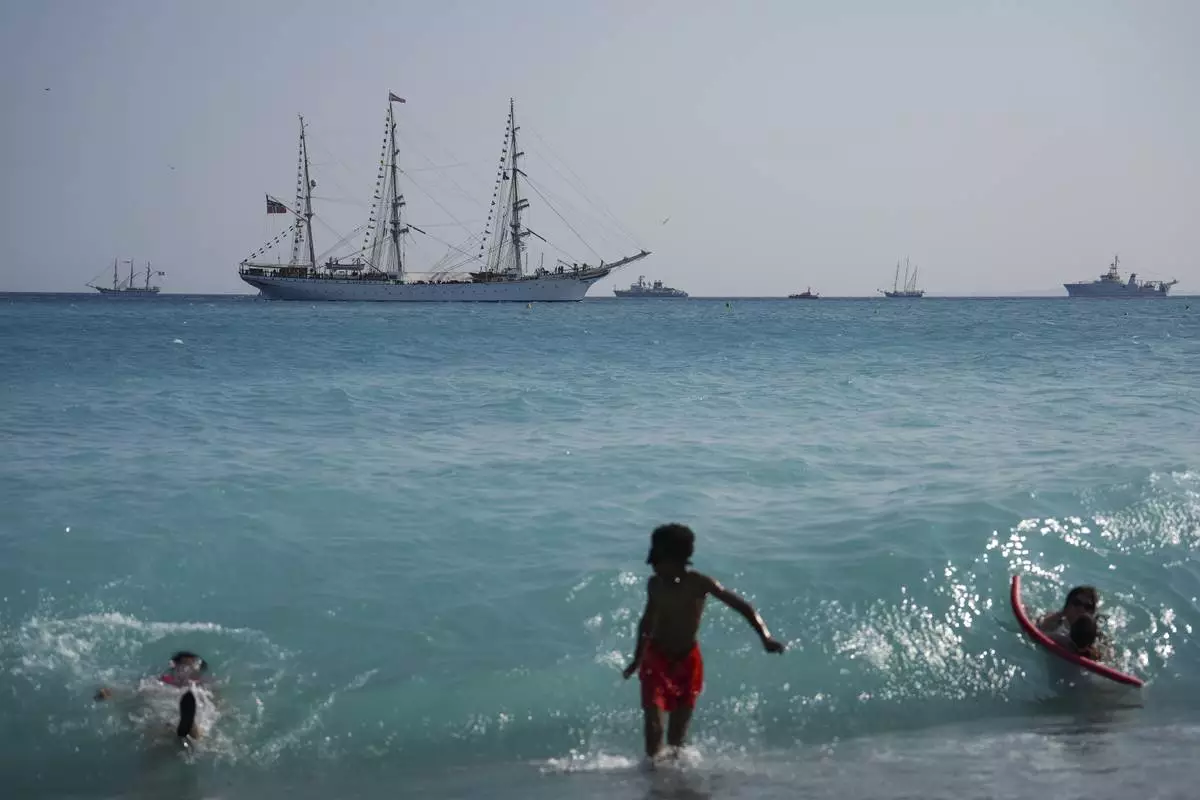 People swim as vessels sail during the "Ocean Wonders" themed event in honor of World Oceans Day ahead of the U.N. Ocean Conference on Sunday, June 8, 2025, in Nice, France. (AP Photo/Annika Hammerschlag)
