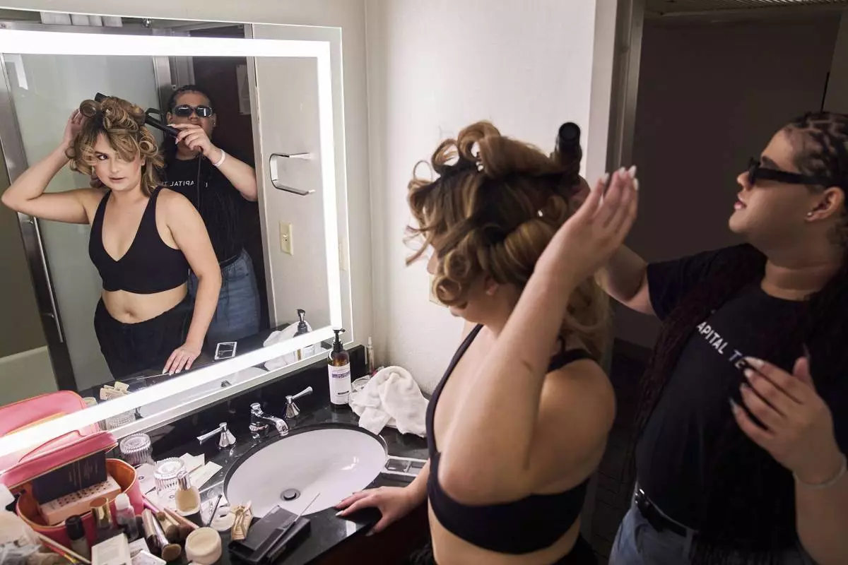 Jae Douglas, 21, a trans femme from Tallahassee, Fla., right, helps Bella Bautista, 22, left, a trans woman, curl her hair in their hotel room in Arlington, Va., Wednesday, June 4, 2025, as the roommates prepare to attend a dinner for strategic organizers of the National Trans Visibility March, during World Pride. (AP Photo/Jacquelyn Martin)