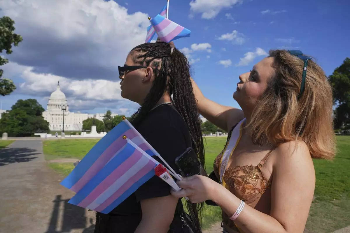 Bella Bautista, 22, right, a trans woman, adjusts the trans pride flags in the hair of trans femme Jae Douglas, 21, as they head toward a concert for World Pride, Saturday, June 7, 2025, by the U.S. Capitol on the National Mall in Washington. (Photo/Jacquelyn Martin)