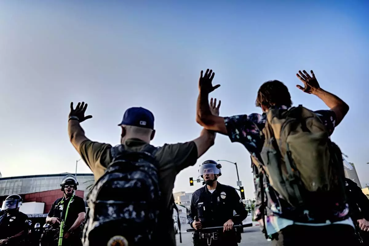 Los Angeles police officers with batons and riot gear attempt to move back protesters in downtown Los Angeles on Monday, June 9, 2025. (AP Photo/Eric Thayer)