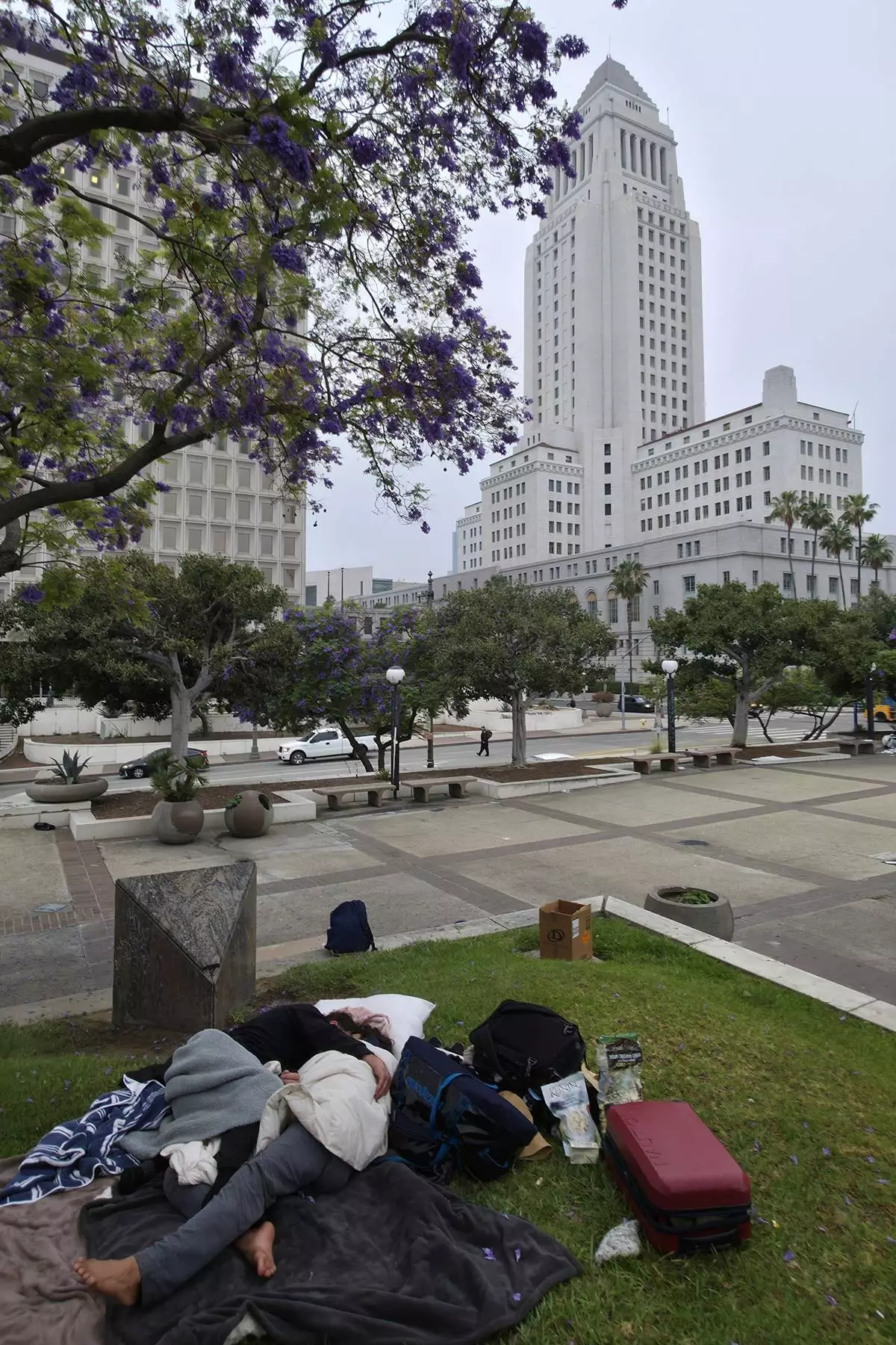 A homeless couple wakes up early morning after sleeping in a public park across the Los Angeles Federal building despite the curfew overnight, Wednesday, June 11, 2025, in Los Angeles. (AP Photo/Damian Dovarganes)