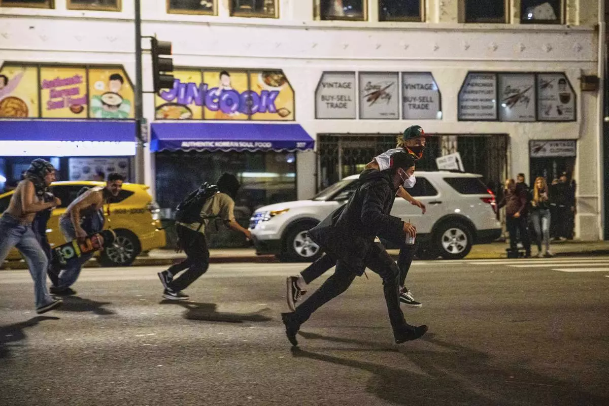 Protesters run to avoid being kettled by police during protests over the Trump administration's immigration raids in Los Angeles, Monday, June 9, 2025. (AP Photo/Ethan Swope)